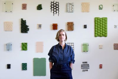 Jacqualin Bradly in front of a wall of her artworks.