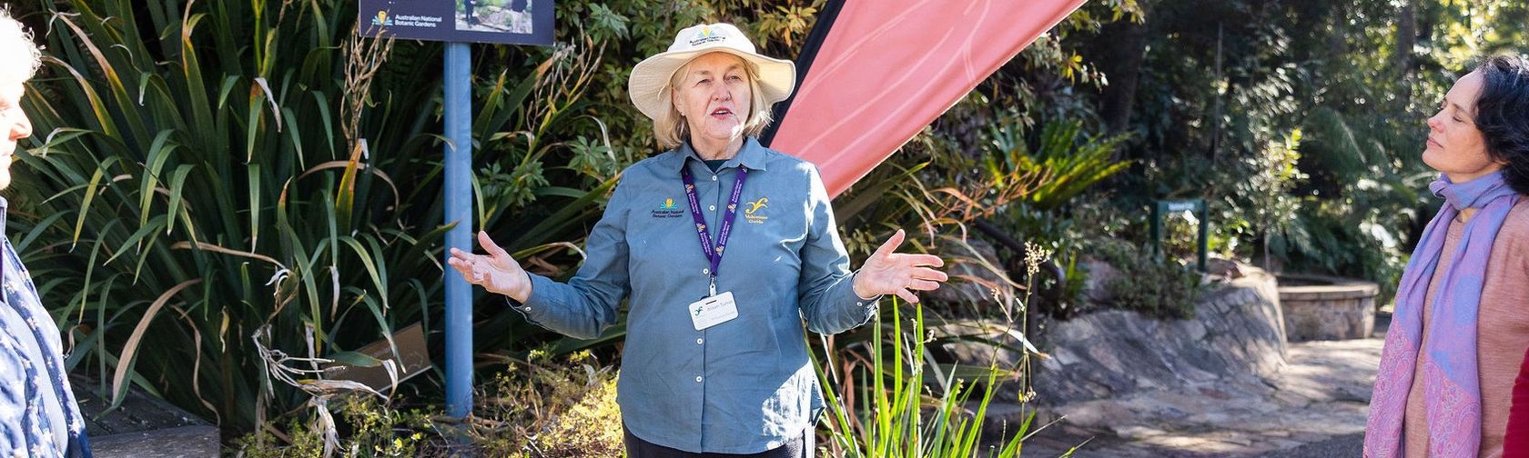 A tour guide presenting to a crowd in the botanic gardens 
