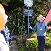 A tour guide presenting to a crowd in the botanic gardens 