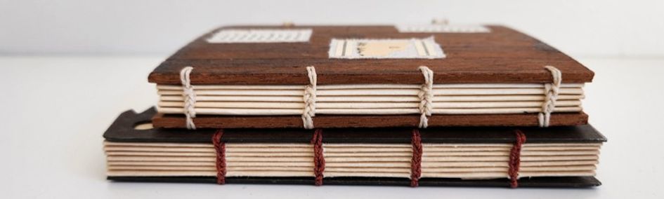 Two books stacked on each other, displaying their coptic stitched spines